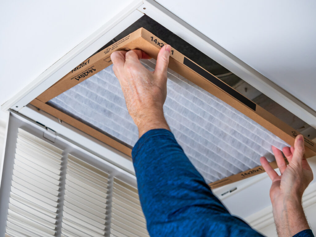 HVAC technician replacing a home air filter in Clovis